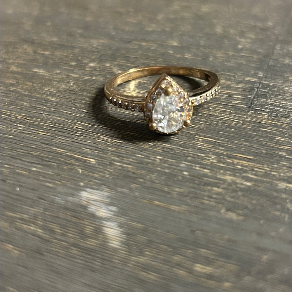 pear-shaped halo ring featuring a moissanite center‎ stone and a pavé band